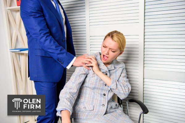 Woman reacting uncomfortably as a man in a blue suit places a hand on her shoulder, with Olen Firm logo in the corner.