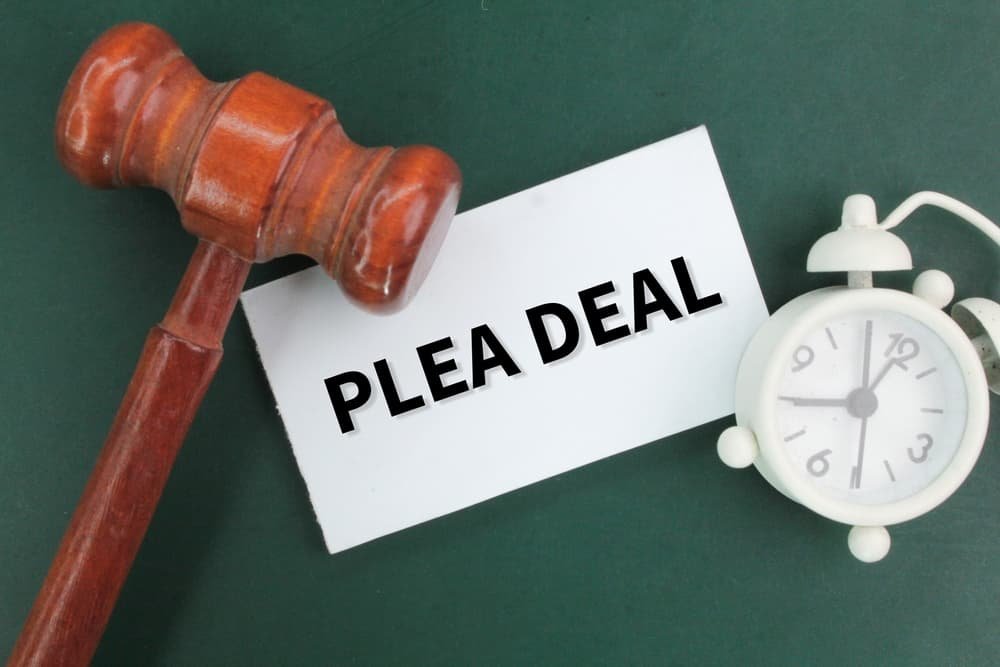 Judge's gavel, bell clock and white paper with the words plea deal in DUI case