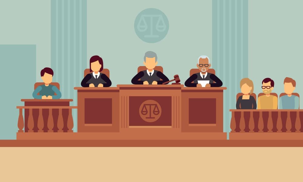 he image shows a courtroom scene. In the center, a judge sits at a raised bench with a gavel, accompanied by two other individuals
