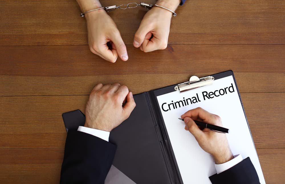 Top view of a police officer reviewing a criminal record at a desk.