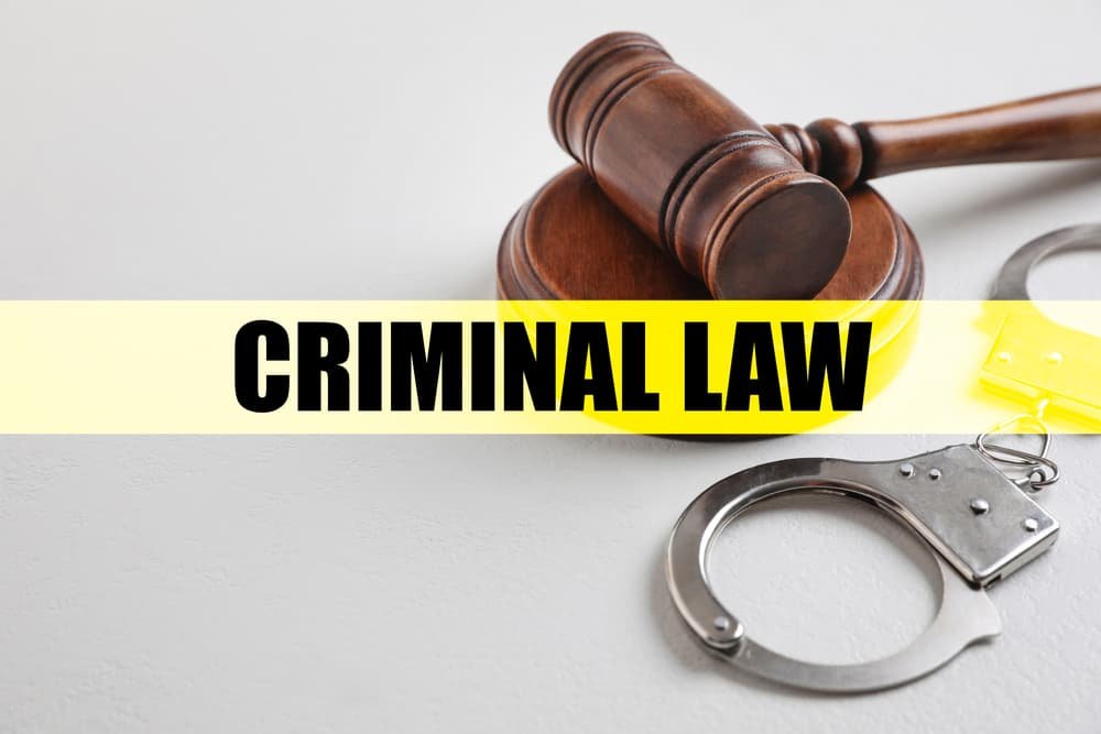 A gavel and handcuffs placed on a white table, symbolizing the concept of criminal law.