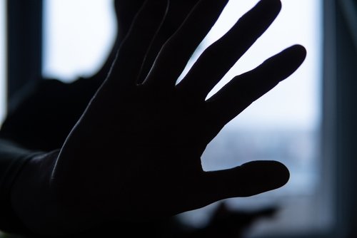 Silhouette of a raised hand blocking the camera, symbolizing refusal or a call to stop.